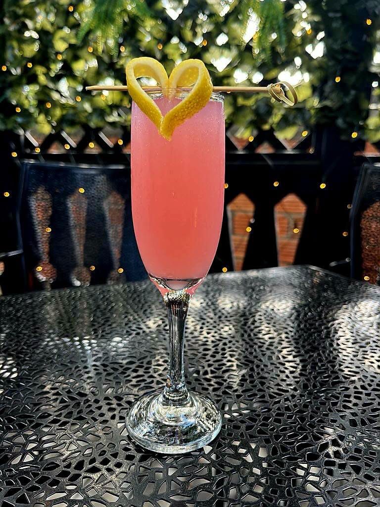The 9 to 5 cocktail, a pink drink in a champagne flute with a heart-shaped lemon twist, at Borracho's
